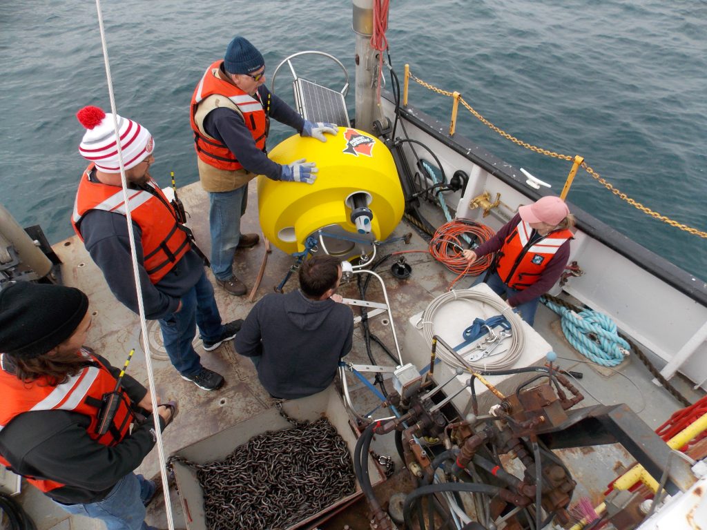 Salmon Unlimited Buoy on a boat next to crew members, surrounded by cables