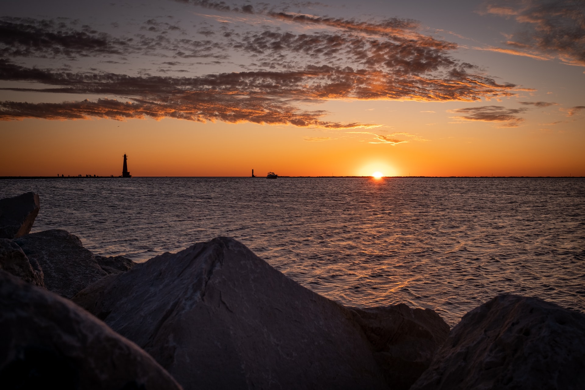 sunset on the water with a lighthouse in the distance