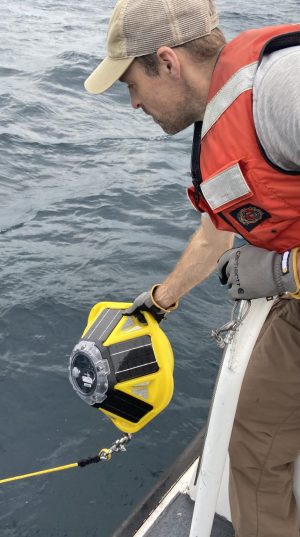 A man drops a small buoy into the water.