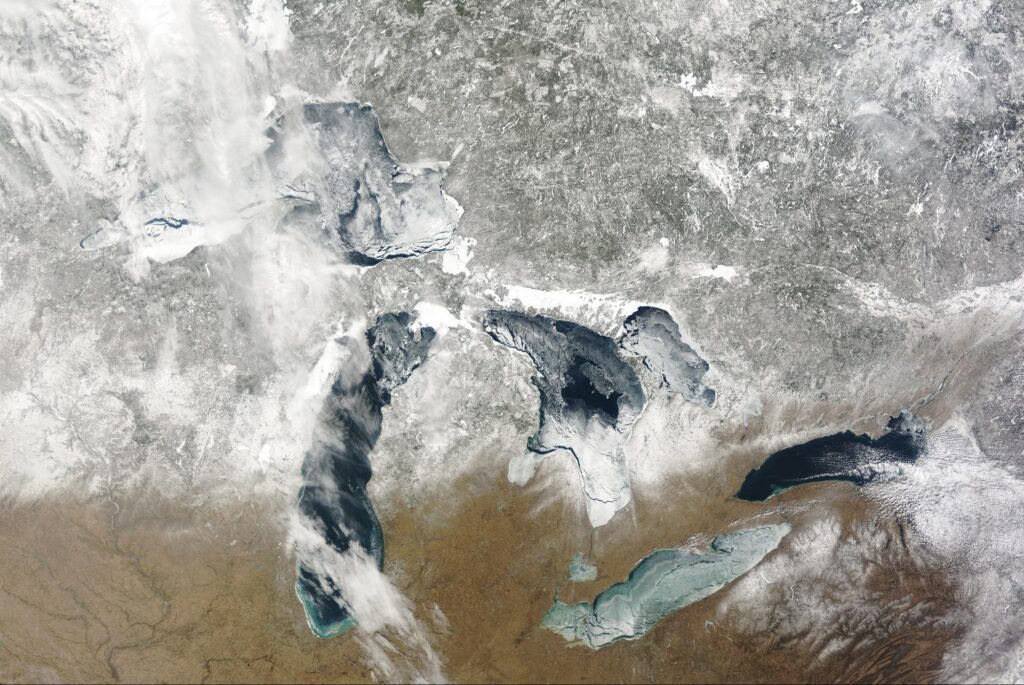 A satellite image showing the Great Lakes, with parts of the lakes covered in ice.